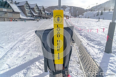 Load Here sign against snow buildings and mountain Stock Photo
