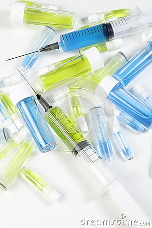 Loaded syringe's and vials containing blue and green fluids Stock Photo