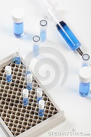 Loaded syringe and vials containing blue fluid Stock Photo