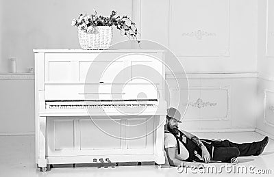 Loader lean on piano instrument. Lazy worker concept. Man with beard, worker in overalls and helmet fall asleep tired Stock Photo