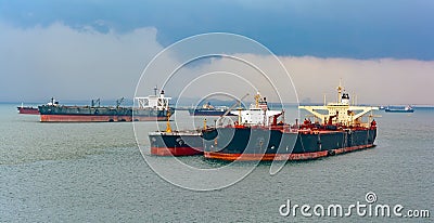 Loading anchored oil supertanker via a ship-to-ship oil transfer Stock Photo