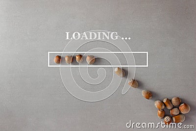Loading background with hazelnuts in progress bar on gray background which is filled with nuts from a heap lying nearby Stock Photo