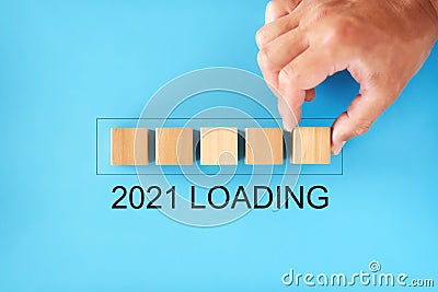 2021 loading concept. man stacks wooden blocks in the form of a progress bar. Stock Photo