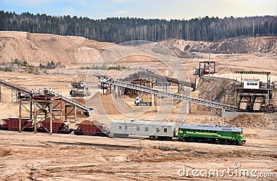 Loading sand into freight cars of a train in quarry. Sand Making Plant in open-pit mining. Crushing factory, machines and Editorial Stock Photo