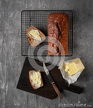 Loaf of home baked banana bread, two slices buttered. Top view Stock Photo