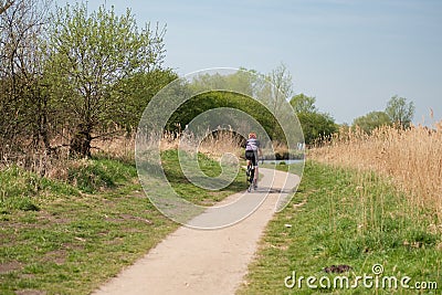 Loan male cyclist wearing cycling clothing seen following a bike trail at a designated conservation area. Editorial Stock Photo