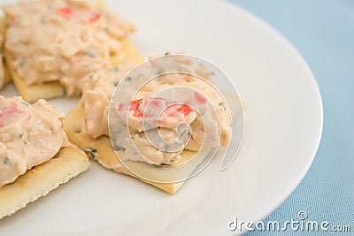 Lobster dip on saltine crackers on blue table cloth Stock Photo