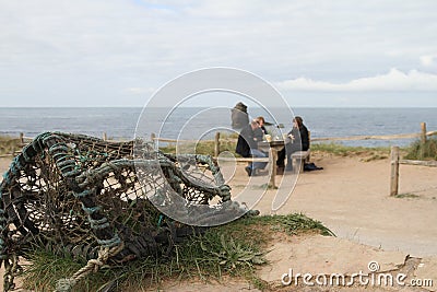 Lobster pot and people by Thurlestone rock Devon. Stock Photo