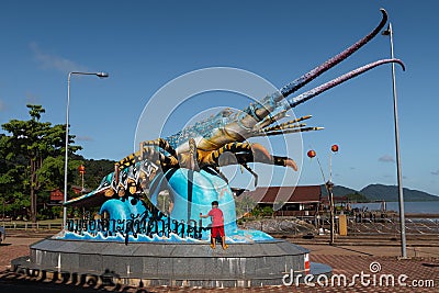 Lobster statue at the Old Town Koh Lanta pier, with child wearing red climbing on it. Ko Lanta, Krabi, Thailand Editorial Stock Photo