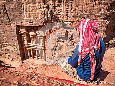 Local arab bedouin man looking at Al-Khazneh The Treasury one of the most elaborate temples in the ancient city of Petra, Jordan Stock Photo