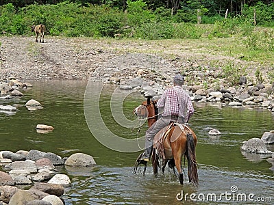 Local cowboy rides a horse through river, Nicaragua Editorial Stock Photo