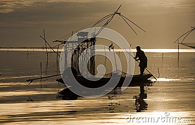 Local fisherman working on his boat in the beautiful en scenic of golden sunset. Stock Photo