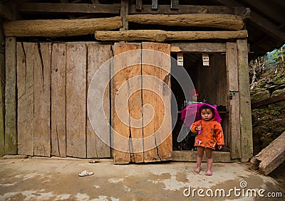 Local Hmong hill tribe woman uses sewing machine while her daughter poses for photo Editorial Stock Photo