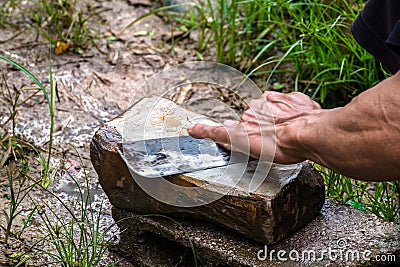 Local male farmer sharpening a knife with whetstone, Stock Photo