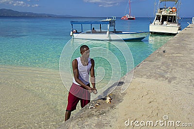 Local man cutting fish in Doctor's Cove Beach in Jamaica, Caribbean Editorial Stock Photo