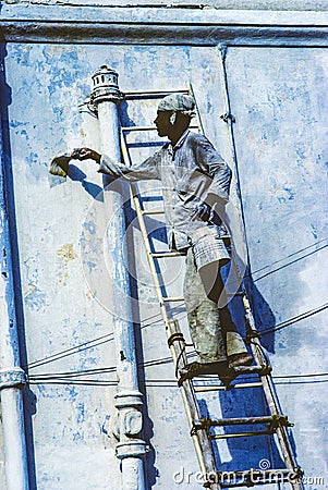 Local painter paints the old wall in the typical blue color Editorial Stock Photo