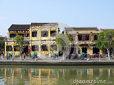 Local people, boats, yellow houses by the river, and tourists in Hoi An ancient town Editorial Stock Photo