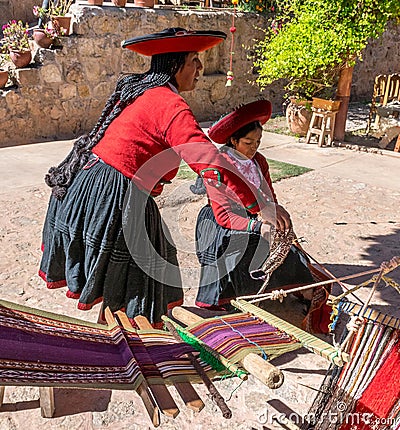 Local Peruvian village women making colorful handmade textiles at textile site in Chinchero, Peru. Editorial Stock Photo