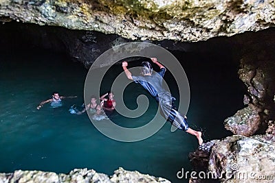 Local Polynesian teens playing and swimming in Veimumuni cave, while a girl jumping to the pool. Motion blur. Vavau, Tonga. Editorial Stock Photo