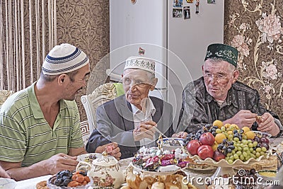 Local residents of Siberian village celebrate Muslim holiday Kurban Bayram at their home table. Mullah talking with Editorial Stock Photo