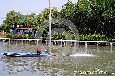 Local Thai fisherman driving traditional wooden thai longtailboat on river lake countryside Thailand Editorial Stock Photo