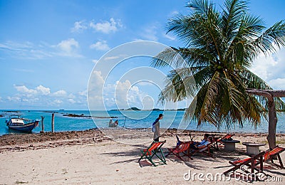 Local Thai tourist sitting on colourful beach beds under coconut Editorial Stock Photo