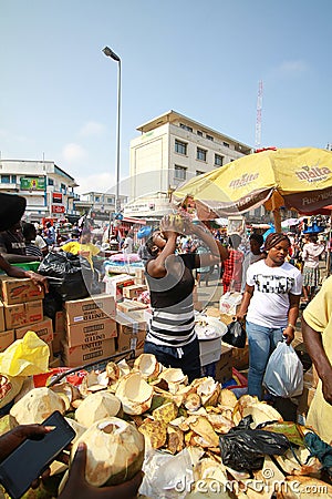 A local trader selling coconuts at a street market in Accra, Ghana Editorial Stock Photo