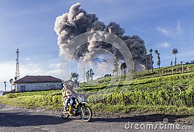 Local village people passing by farming land as the ash from the volcano goes high in the sky when Mt Bromo erupted during Januar Editorial Stock Photo