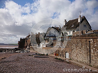 Local vintage historical cottage houses with straw roofing and high stone walls by the seaside beach Stock Photo
