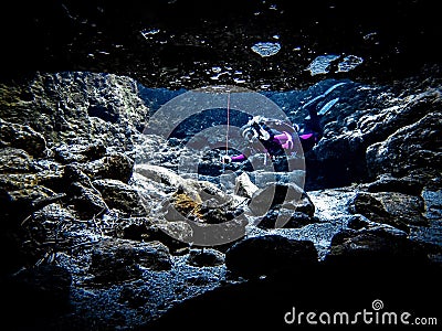 Local woman scuba diver peeks into the cavern at Devil's Eye, Ginnie Springs, Florida Editorial Stock Photo