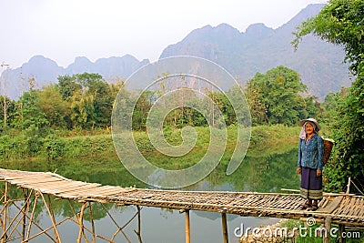 Local woman with traditional clothes at wooden bridge in Vang Vieng, Laos Editorial Stock Photo
