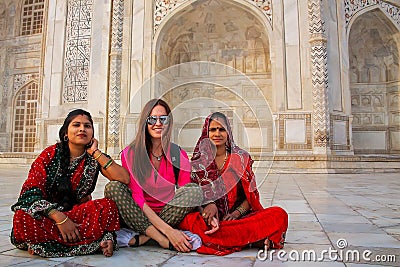 Local women and a foreign girl sitting outside Taj Mahal in Agra Editorial Stock Photo