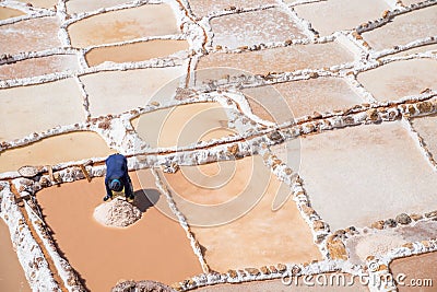 Local worker extracing salt from Maras salt mine, Urubamba, Cusco, Peru, South America Stock Photo