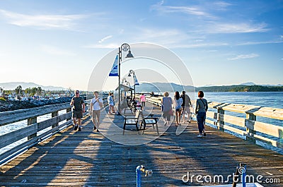 Locals and Tourists strolling along a Fishing Pier at Sunset Editorial Stock Photo