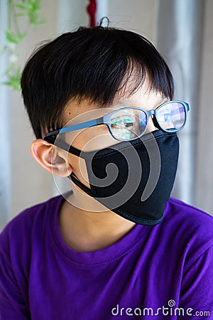 Lockdown and school closures. School boy wearing glasses showing outdoor reflection light with face mask feeling bored and Stock Photo