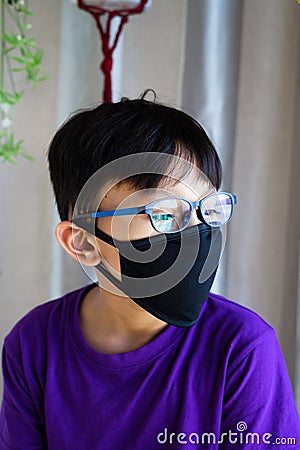 Lockdown and school closures. School boy wearing glasses showing outdoor reflection light with face mask feeling bored and Stock Photo