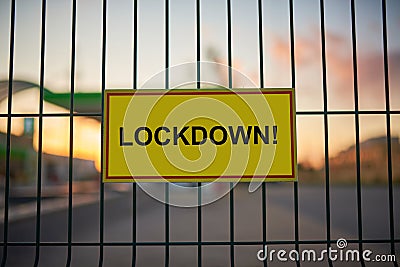 Lockdown sign on a fence with blured city view on a background at sunset Stock Photo