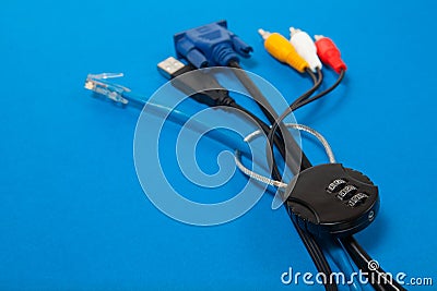 Locked cipher padlock and various cables on blue background. Stock Photo