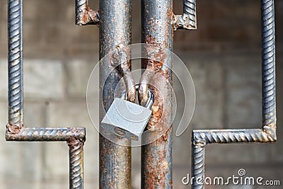 Locked lock old rusty metal door close up. Antique slide steel locked shutter door. The lock, on the grating, closed Stock Photo