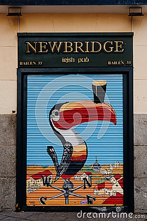 Locked roll-up door painted with the image of a toucan from an Irish pub in Madrid Editorial Stock Photo