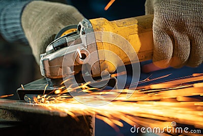 Locksmith in special clothes and goggles works in production. Metal processing with angle grinder. Sparks in Stock Photo