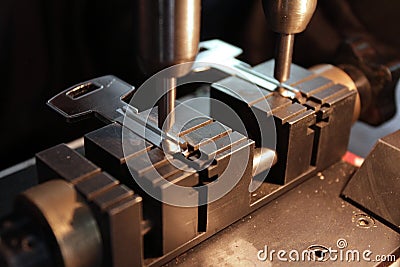 Locksmith in workshop makes new key. Professional making key in locksmith. Person who makes and repairs keys and locks. Key maker. Stock Photo