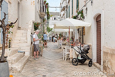 Tourists enjoying the outdoor restaurants in the ancient village Locorotondo, in province of Bari, Italy Editorial Stock Photo