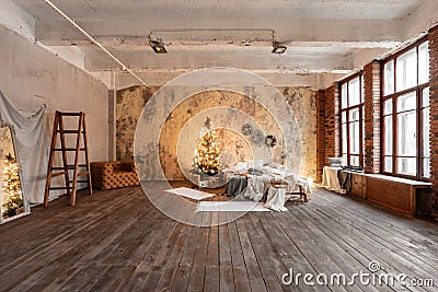 Loft style apartments. Bed in the bedroom, high large Windows. Brick wall with candles and Christmas tree. warm and Stock Photo