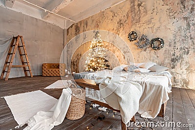 Loft style apartments. Bed in the bedroom, high large Windows. Brick wall with candles and Christmas tree. warm and Stock Photo