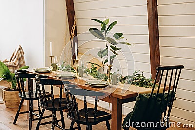 The loft dining table is decorated with flowers, candles and herbs. Soft selective focus Stock Photo