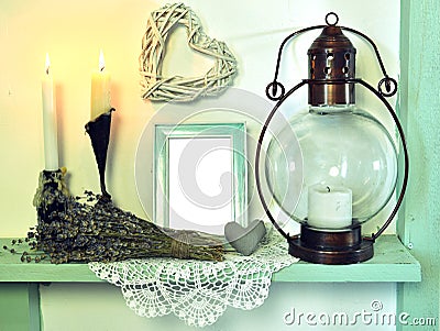 Old lamp, burning candles, lavender and picture frame with heart decoration on shelf Stock Photo