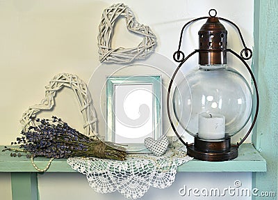 Old lamp, lavender bunch, picture frame and heart decoration on wooden shelf with napkin Stock Photo