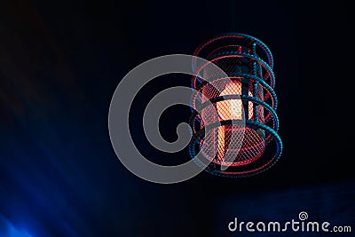 Loft pendant lamp with red blue glow in steel rebar shade, wooden interior background, copy space Stock Photo