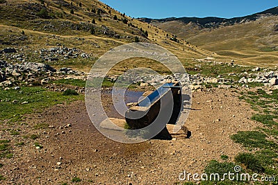 A log hollowed out for water, water for domestic cattle sheep, goats, etc. and wild animals, with blurred mountain peaks. Stock Photo